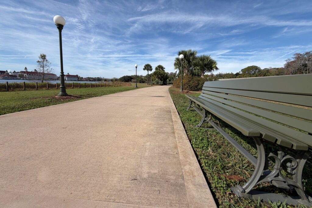 green bench on pathway next to lake