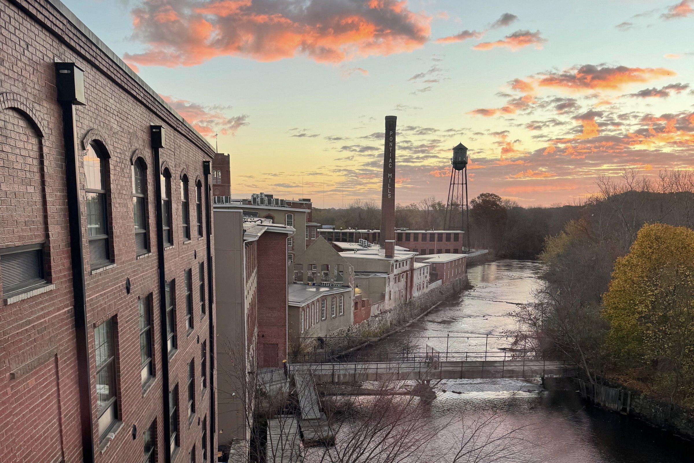 pink and orange skies from a sunset over a river and old mill during early fall