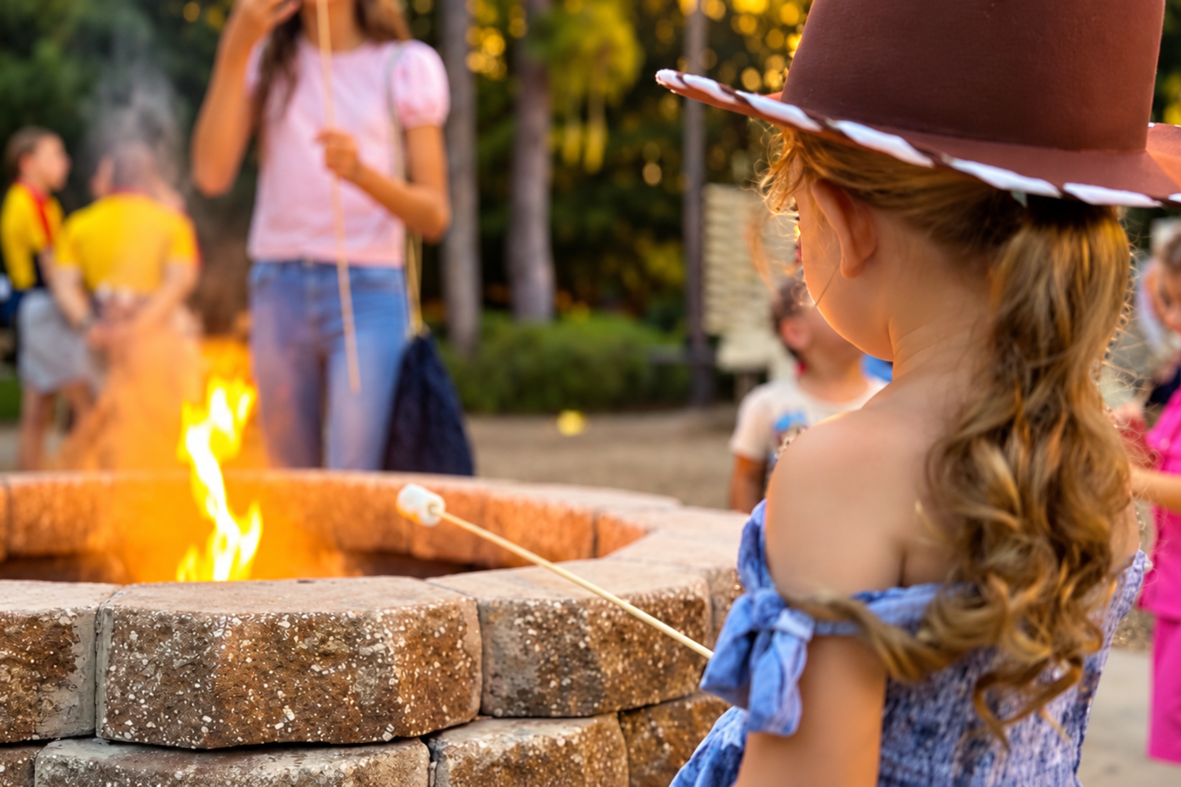 A young girl in a cowboy hat roasts marshmallows over a campfire at Disney's Fort Wilderness Resort & Campground.